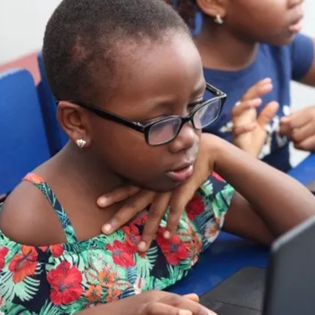 A rural community leader teaching digital skills to local youth using laptops and smartphones.