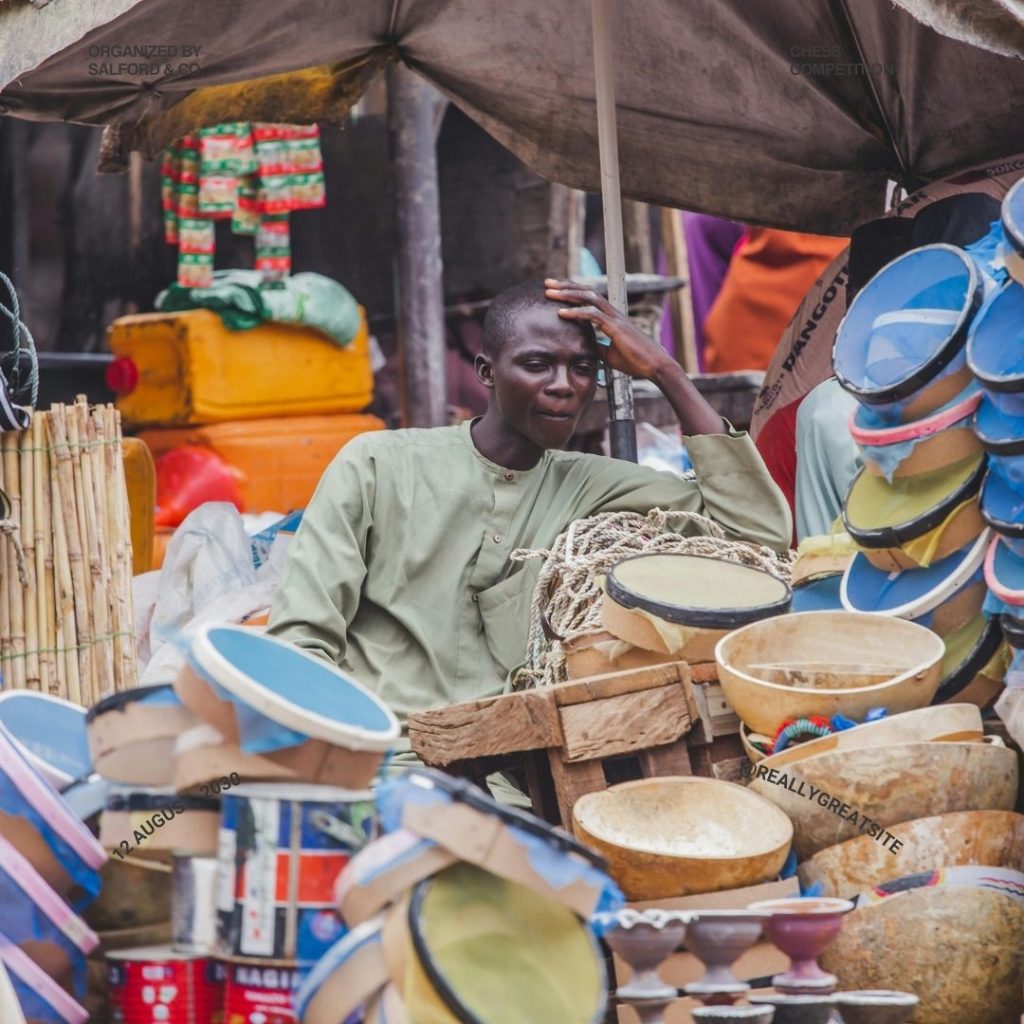 A bustling Nigerian market with vendors selling handmade crafts